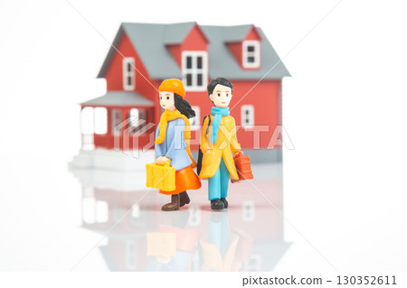 Miniature characters carrying luggage near a red house in a bright setting Miniature characters carrying luggage near a red house in a bright setting 130352611