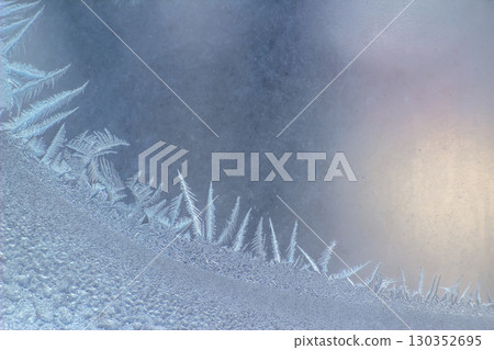 Frost patterns create a stunning winter display on a window in early morning light Frost patterns create a stunning winter display on a window in early morning light 130352695