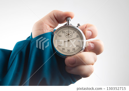 Hand holding a stopwatch to measure time in a simple indoor setting Hand holding a stopwatch to measure time in a simple indoor setting 130352715