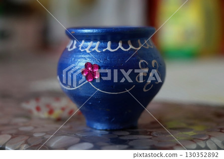 Hand-painted blue decorative pot (matka) with floral motifs, used for puja rituals, festive decoration, and Indian cultural traditions. 130352892