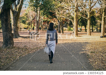 Back view of a businesswoman walking in an autumn park 130354125
