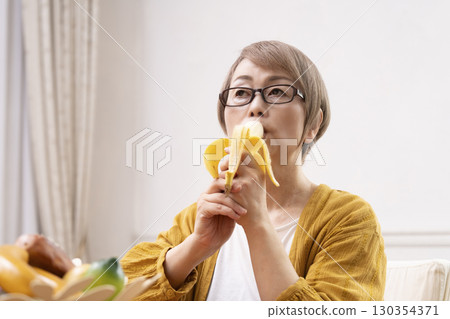一位老年婦女在餐廳剝香蕉並吃香蕉 130354371