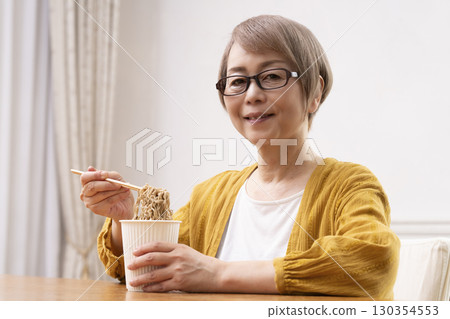 一位老年婦女在餐廳吃泡麵 一位老年婦女在餐廳吃泡麵 130354553
