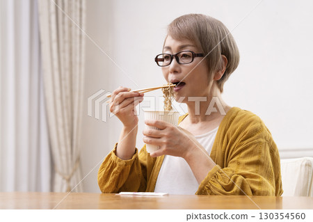 一位老年婦女在餐廳吃泡麵 130354560