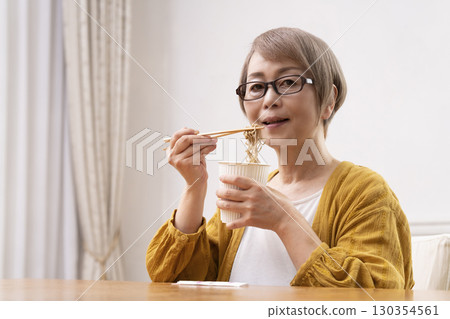 Senior woman eating instant noodles in the dining room Senior woman eating instant noodles in the dining room 130354561