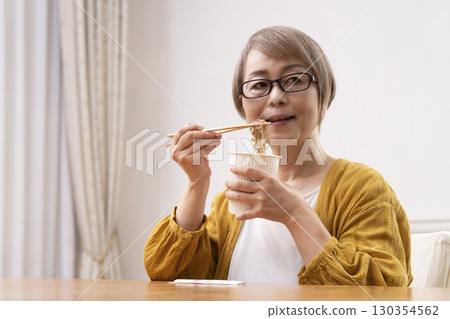 Senior woman eating instant noodles in the dining room Senior woman eating instant noodles in the dining room 130354562