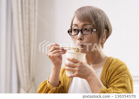 Senior woman eating instant noodles in the dining room 130354570
