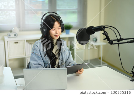 Young woman recording podcast at home studio, and speaking into microphone Young woman recording podcast at home studio, and speaking into microphone 130355316