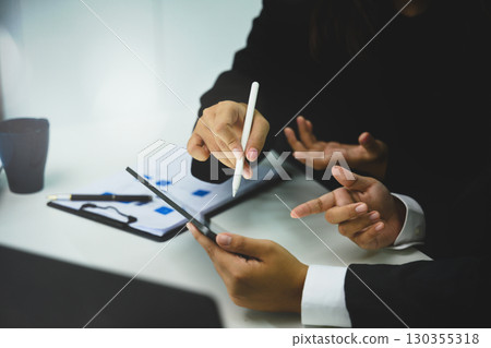 Corporate team brainstorming, using digital tablet and reports for project management 130355318