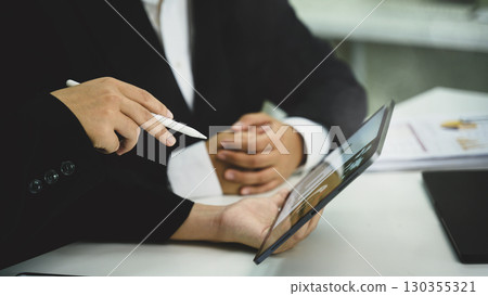 Colleagues analyzing financial data and workflow charts with digital tablet in an office 130355321