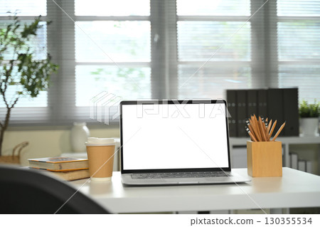 Laptop with blank screen on office desk beside takeaway coffee cup, and pencil holder Laptop with blank screen on office desk beside takeaway coffee cup, and pencil holder 130355534