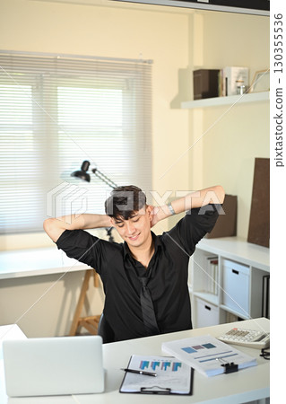 Relaxed office worker taking a break after working on financial reports Relaxed office worker taking a break after working on financial reports 130355536