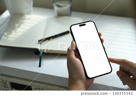 Close up of person holding smartphone with blank screen, finger pointing at display 130355543