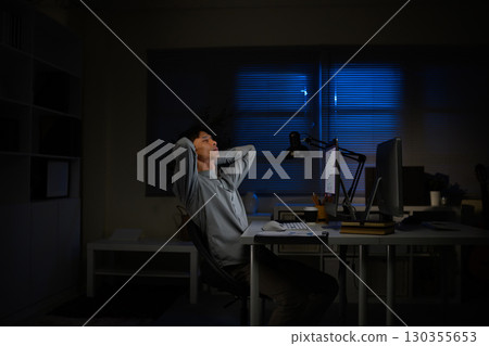 Tired businessman stretching in office chair, exhausted after long hours of computer work Tired businessman stretching in office chair, exhausted after long hours of computer work 130355653