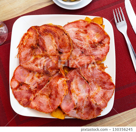 Sliced Galician lacon ham with paprika on plate 130356245