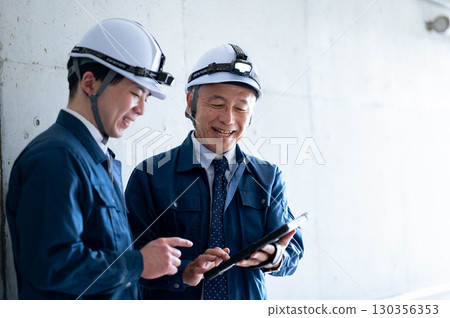 Young and veteran workers in work clothes 130356353