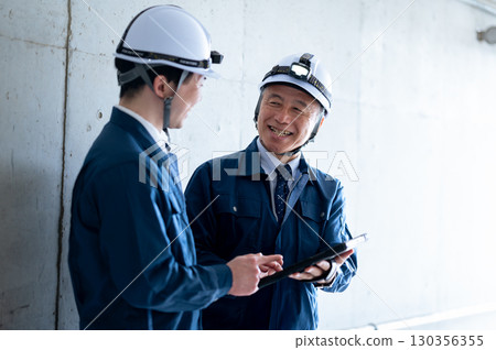 Young and veteran workers in work clothes 130356355