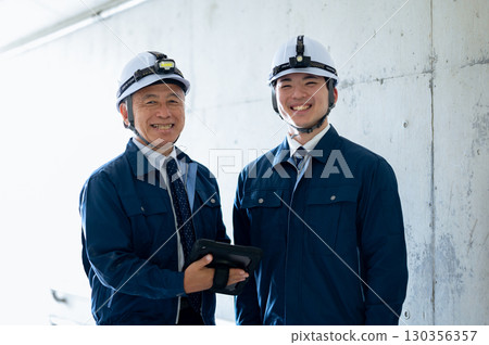 Young and veteran workers in work clothes 130356357
