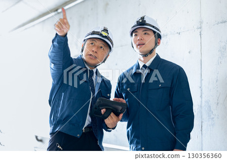 Young and veteran workers in work clothes 130356360