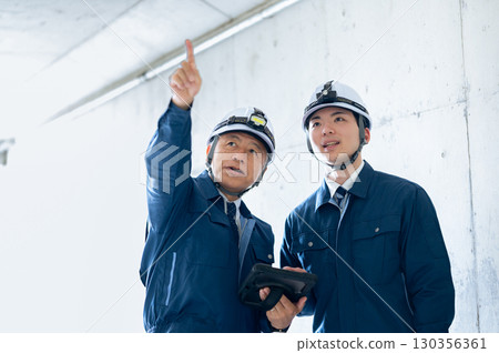 Young and veteran workers in work clothes 130356361