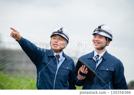 Young and veteran workers in work clothes 130356366