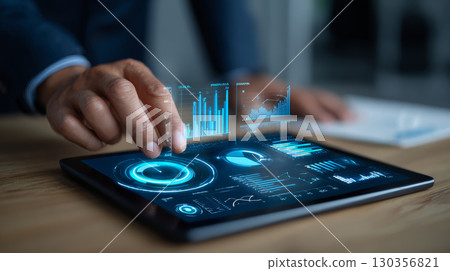 Businessman using digital tablet with futuristic financial data and charts hologram, showing innovation and technology in business analysis 130356821