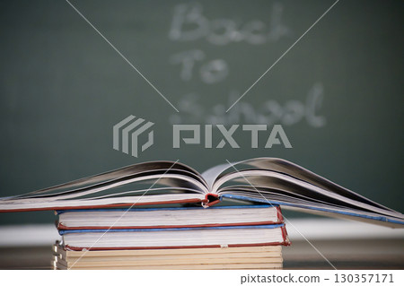 Open book on top of a stack of books with a chalkboard background. Open book on top of a stack of books with a chalkboard background. 130357171