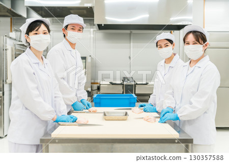 Male and female staff in chef coats preparing chicken (chef, chef, fresh market, food processing) 130357588