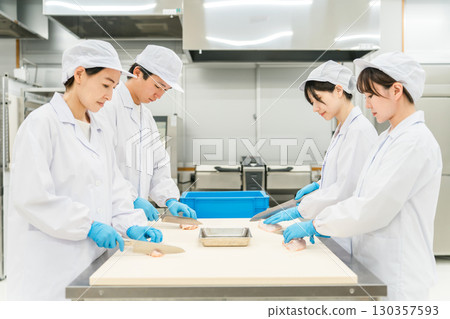 Male and female staff in chef coats preparing chicken (chef, chef, fresh market, food processing) 130357593