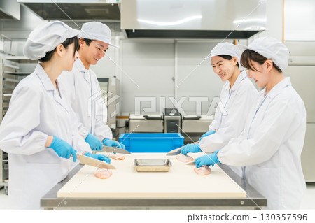 Male and female staff in chef coats preparing chicken (chef, chef, fresh market, food processing) Male and female staff in chef coats preparing chicken (chef, chef, fresh market, food processing) 130357596