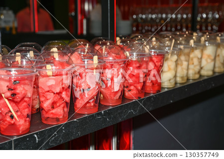 Cups filled with fresh watermelon and melon pieces served as vegan snacks on a party table, ready for guests as healthy summer refreshments. Cups filled with fresh watermelon and melon pieces served as vegan snacks on a party table, ready for guests as healthy summer refreshments. 130357749