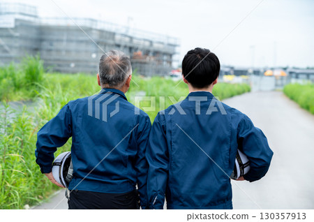 The backs of two people supporting the construction site 130357913