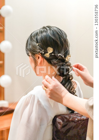 Bride and groom preparing for the wedding ceremony and reception in the bridal room (hair and makeup, hair styling) 130358736