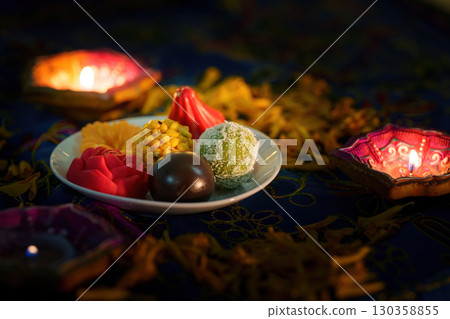 Diwali Celebration: Colorful Sweets and Diyas on Festive Table 130358855