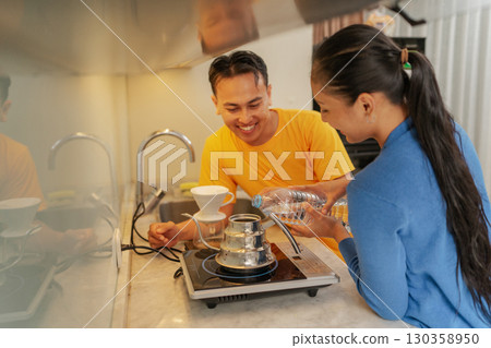 A Couple Enjoying a Fun and Joyful Coffee Brewing Moment in Their Modern Kitchen 130358950
