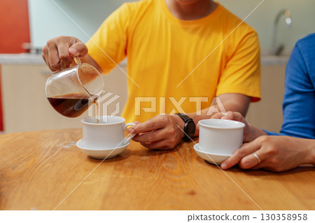 Pouring Fresh Brewed Coffee into Cups at a Cozy Caf Table Pouring Fresh Brewed Coffee into Cups at a Cozy Caf Table 130358958