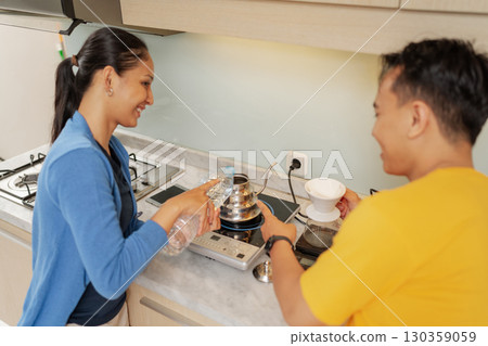 A Couple is Delightfully Enjoying Cooking Together in a Modern Kitchen Setting A Couple is Delightfully Enjoying Cooking Together in a Modern Kitchen Setting 130359059