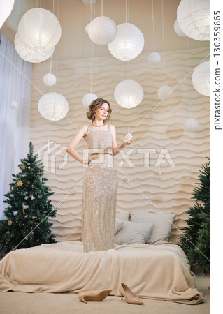 Elegant woman in sparkling dress posing with star among holiday decorations Elegant woman in sparkling dress posing with star among holiday decorations 130359865