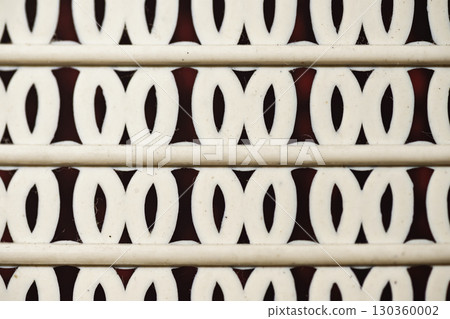 Closeup detail of a horizontal pattern comprised of parallel lines interspersed with repeating oval shapes against a contrasting dark background. Geometric textures background Closeup detail of a horizontal pattern comprised of parallel lines interspersed with repeating oval shapes against a contrasting dark background. Geometric textures background 130360002