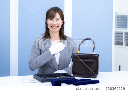 一位女士在採購公司的櫃檯評估一件商品 一位女士在採購公司的櫃檯評估一件商品 130360229