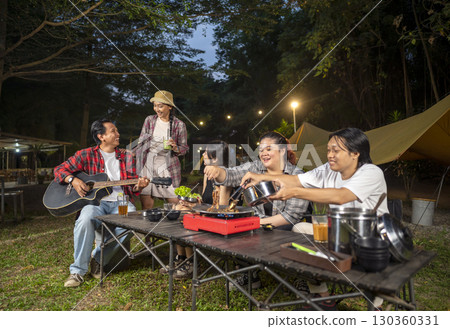 Indonesian southeast asian people cooking sliced marinated beef bulgogi on a grill pan. One of them is holding an acoustic guitar. Scene of the lifestyle of enjoying food in a natural setting Indonesian southeast asian people cooking sliced marinated beef bulgogi on a grill pan. One of them is holding an acoustic guitar. Scene of the lifestyle of enjoying food in a natural setting 130360331