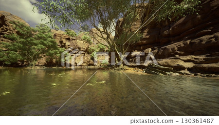 Clear waters reflect rock formations in this tranquil oasis surrounded by lush greenery. The sunlight illuminates the stunning natural features under a bright sky. 130361487