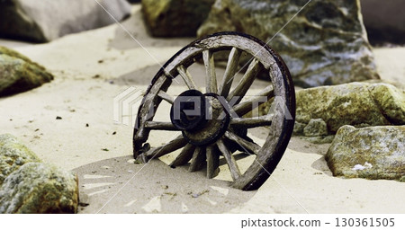 A wooden wagon wheel rests among sandy soil and scattered rocks. Its weathered surface and strategic positioning suggest a long lost history in this natural setting. 130361505