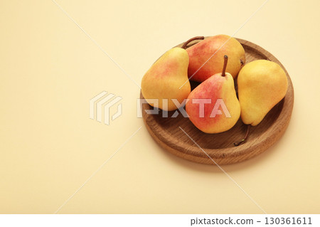 Fresh pear fruit on wooden plate on beige background. Healthy fruit 130361611