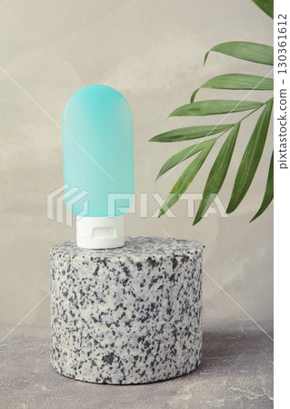 Cosmetic bottle with green leaves on grey background. Space for text 130361612
