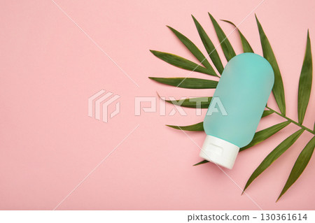 Cosmetic bottle with green leaves on pink background. Space for text 130361614