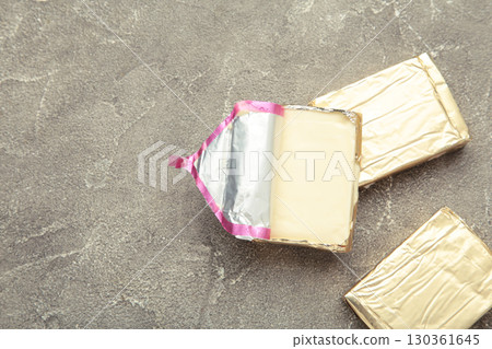 Processed cheese in foil on grey background Processed cheese in foil on grey background 130361645