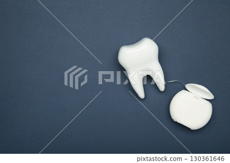 Healthy dental equipment tools for dental care. Plastic tooth with dental floss on dark blue Healthy dental equipment tools for dental care. Plastic tooth with dental floss on dark blue 130361646