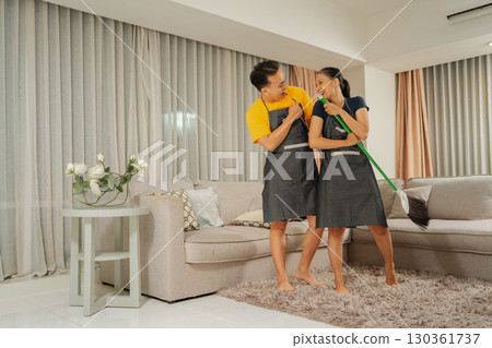 A Couple Happily Enjoying a Fun Cleaning Session Together in Their Modern Living Room 130361737