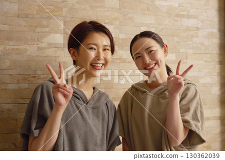 Two women using the sauna making a peace sign 130362039